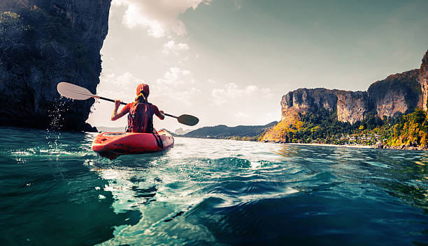 Lady paddling the kayak in the calm tropical bay